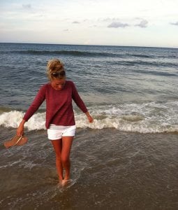 Woman on beach in loose a-line sweater with three quarter length sleeves