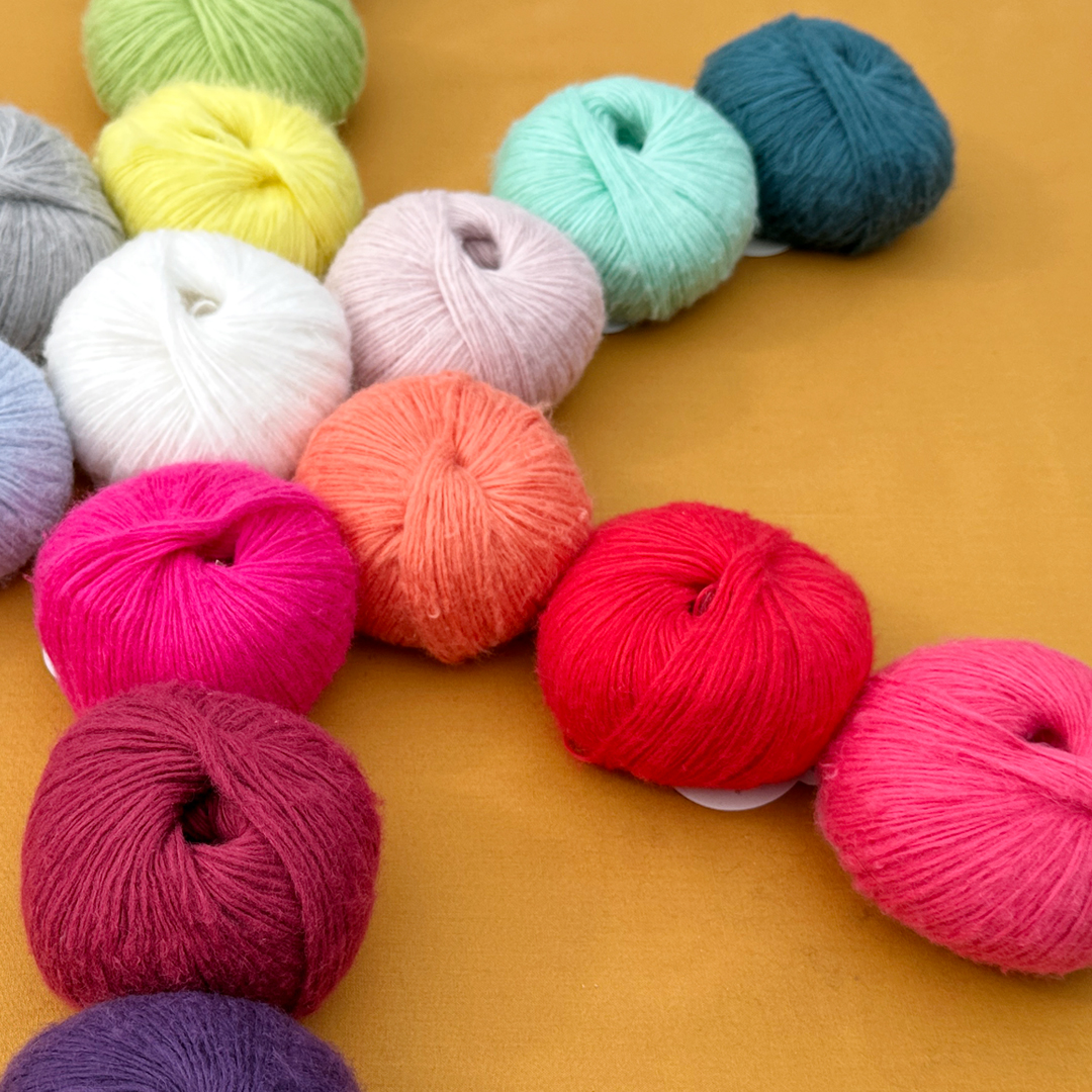 Colorful balls of soft, fuzzy yarn arranged in a star shape on a warm yellow background.