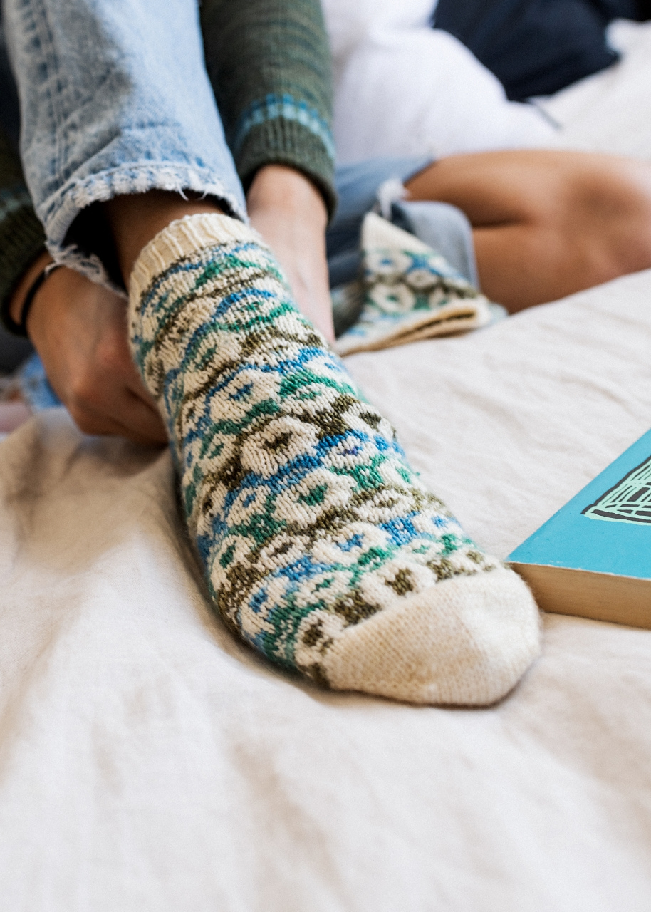 Closeup on a person's foot in a stranded colorwork sock with a colorful sheep design.