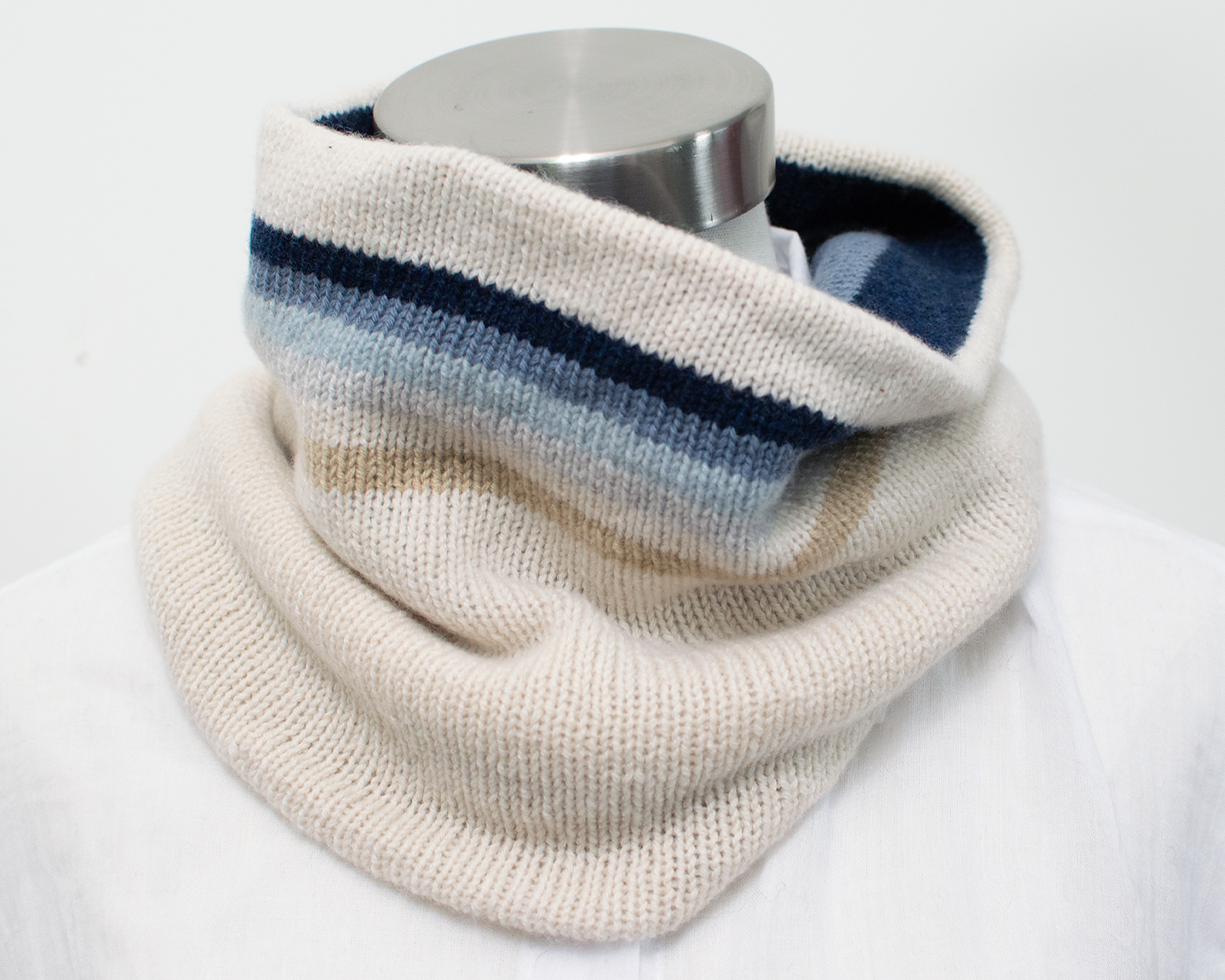 A double-sided cowl in soft white cashmere with gradient stripes in shades of blue from light to dark.