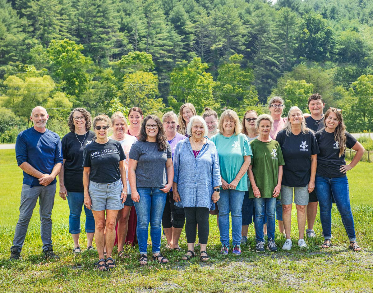 The staff of Miss Babs Hand-Dyed Yarns stand on a sunny lawn with lush green trees in the background.
