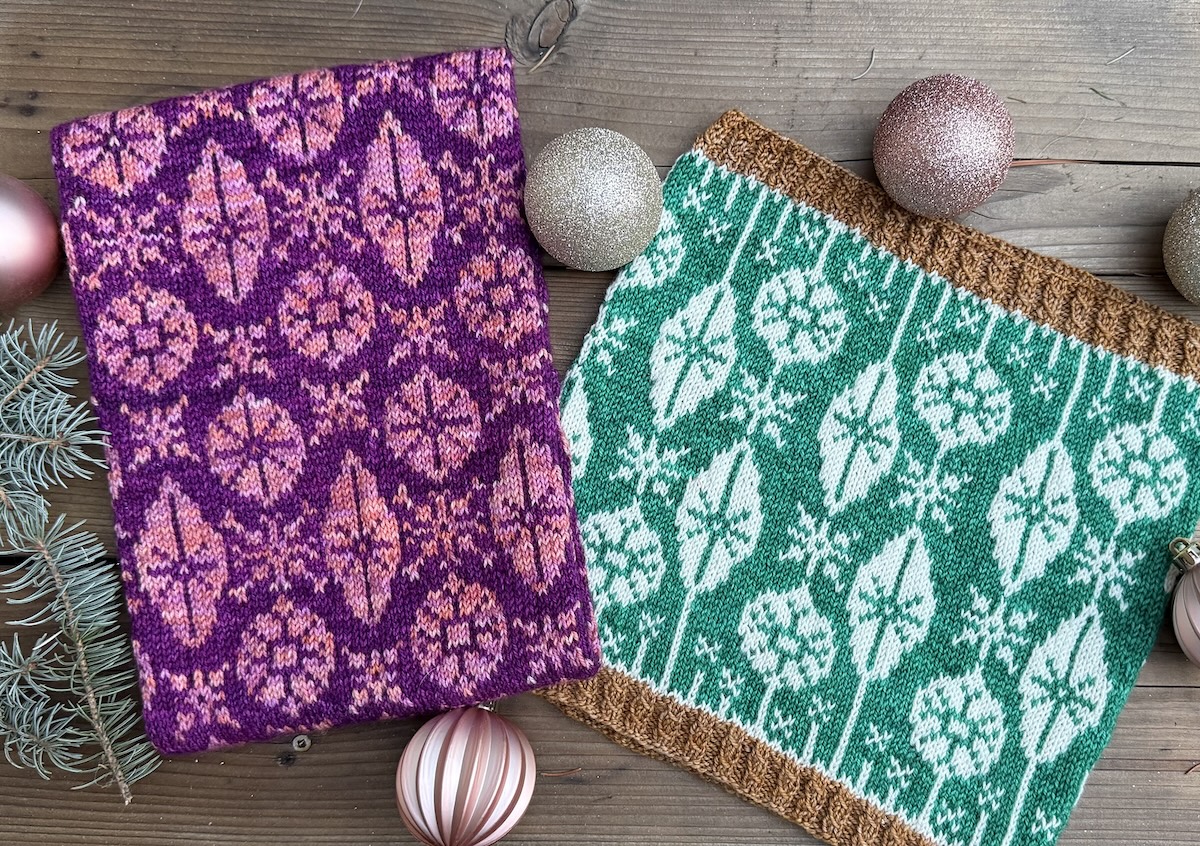 Two cowls knitted in a retro Christmas ornament motif in vibrant shades of pink and green lie on a table scattered with pale gold ornaments.