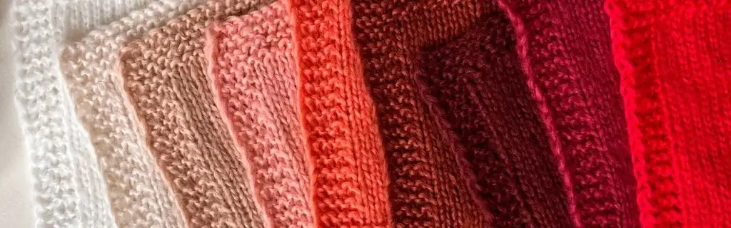 Fuzzy knitted swatches in shades of white, beige, warm pink, ,and reds.