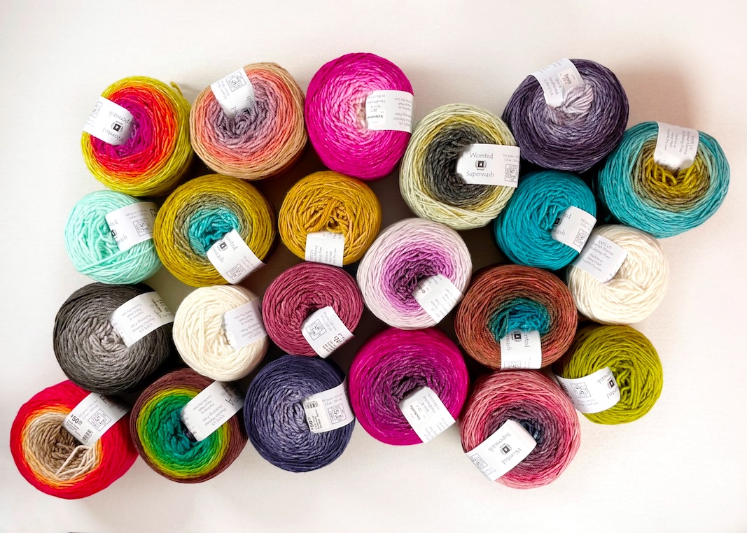 Several balls of colorful hand dyed gradient yarn on a white background