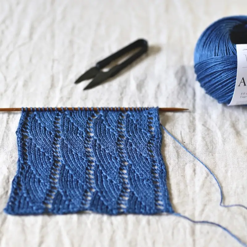 A knitted lace swatch in deep blue linen yarn.