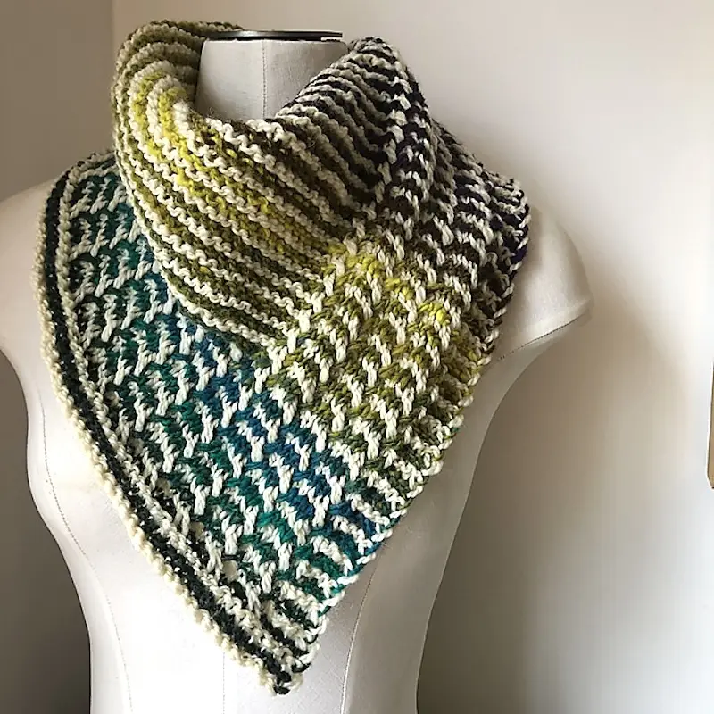 A knitted bandana striped in shades of blue and green on a dress form