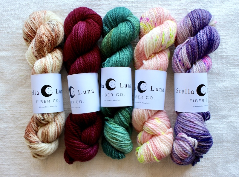 Skeins of hand dyed Stella Luna yarn in variegated and tonal brown, deep red, cool green, bright peach, pink and purple shades.