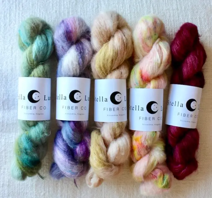 Fluffy hand dyed skeins of alpaca and silk yarn in bright purple, green, peach, and magenta shades.