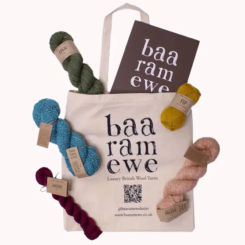 A canvas tote bag with the Baa Ram Ewe logo and several skeins of their yarns.