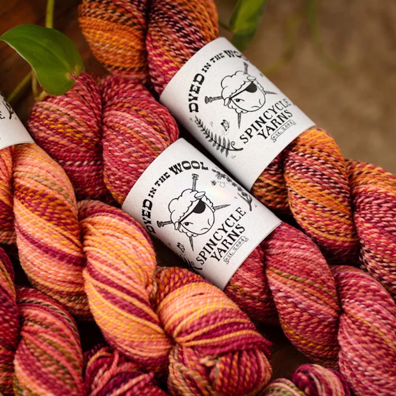 Skeins of Spincycle Yarns Dyed In The Wool in a marled red-orange colorway.