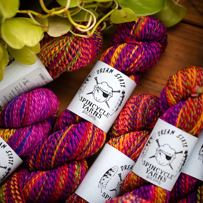 Multicolored marled skeins of Spincycle Yarns Dream State yarn in bright pink, purple, orange, yellow and green.