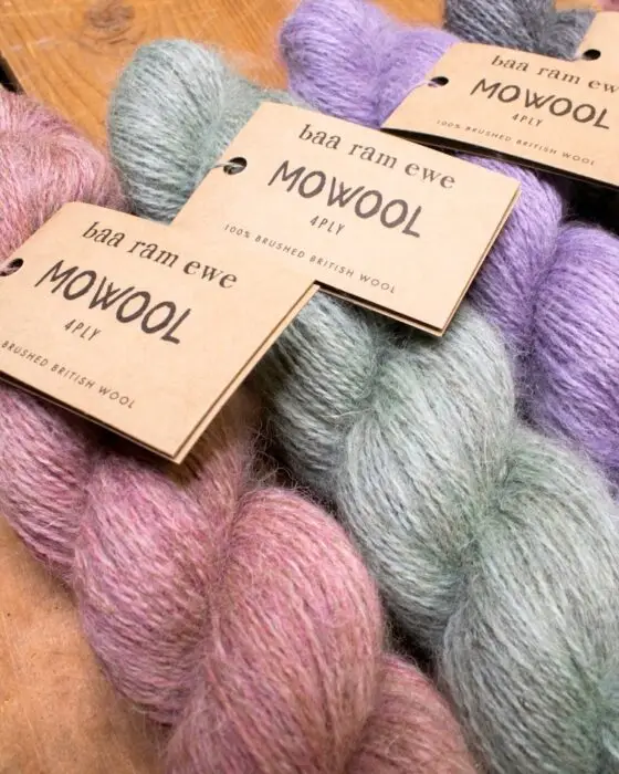 Skeins of Baa Ram Ewe Mowool yarn in soft pink, green, and purple.