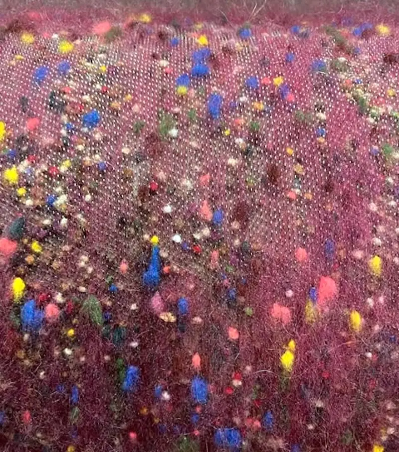 Closeup of wool tweed nepps being carded into dyed wool.