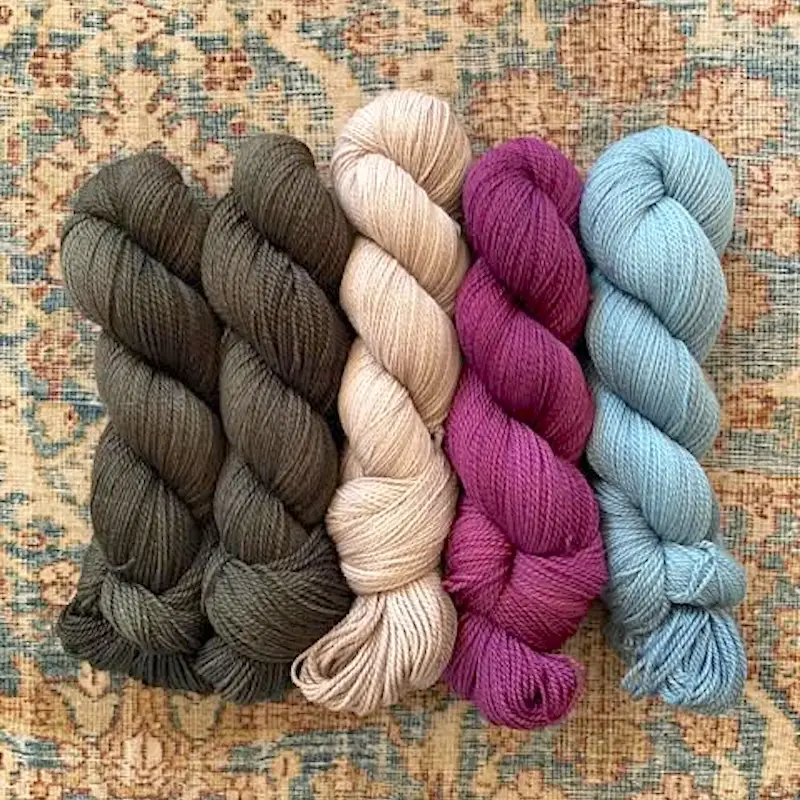 Five skeins of Little Fox Yarn TrueWash Fine in brown, cream, magenta and pale blue.
