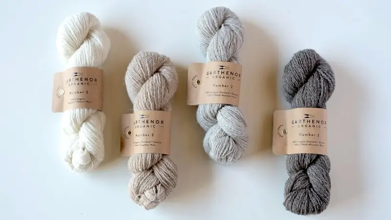 Four skeins of Garthenor Organic Number 2 yarn ni white, beige, pale gray, and charcoal