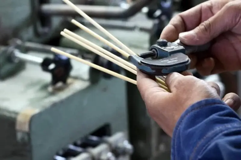 Bamboo dowels being measured with calipers in the factory.