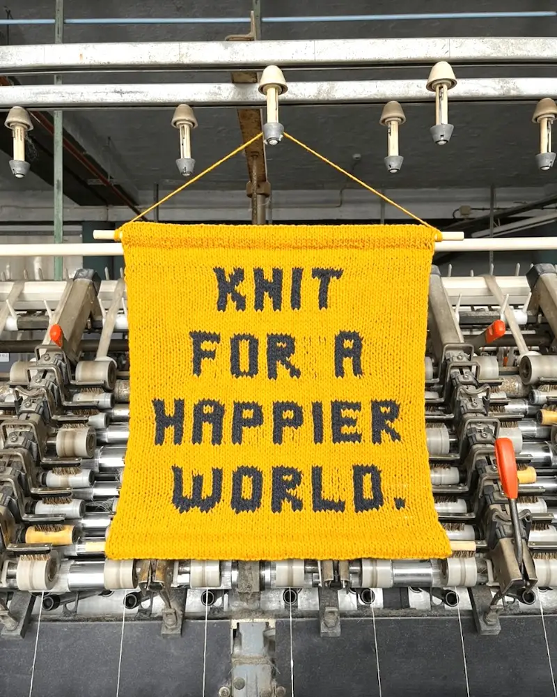 A knitted banner reading "Knit For a Happier World".