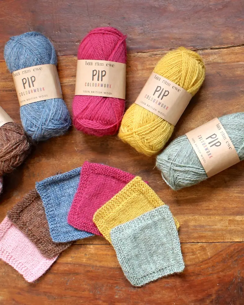 Skeins and swatches of Baa Ram Ewe Pip yarn in pale pink, brown, blue, hot pink, yellow, and pale green