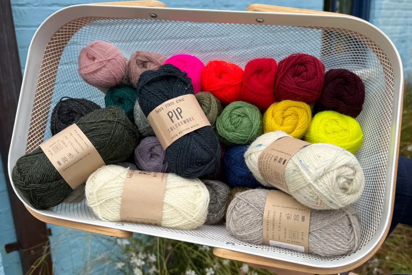 A basket of Baa Ram Ewe Pip fingering weight yarn in brights, earth tones, and neutral shades
