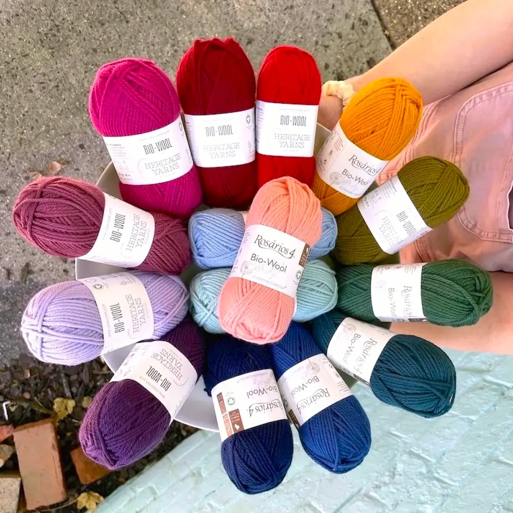 A person's arms holding a basket of colorful BioWool skeins arranged in a circle