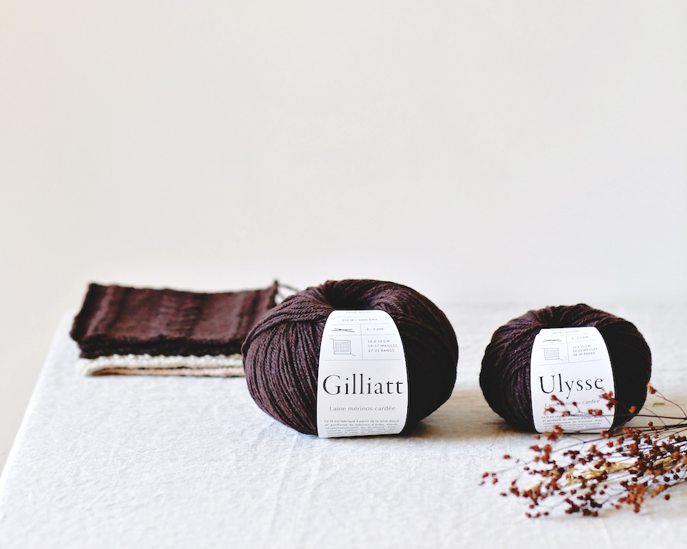 Balls and swatches of De Rerum Natura Gilliatt and Ulysse yarns on a linen-covered table.