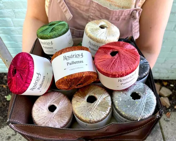 Closeup of a person holding a basket of sparkly sequined yarn balls